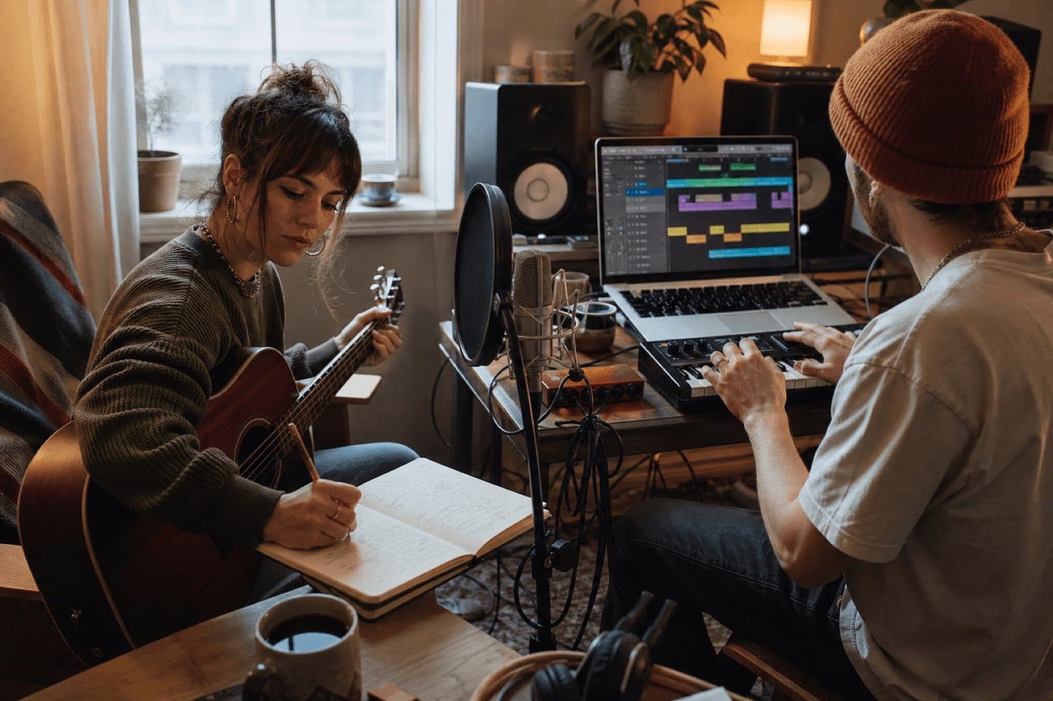 Two real musicians writing, playing guitar, and producing a song in a home studio